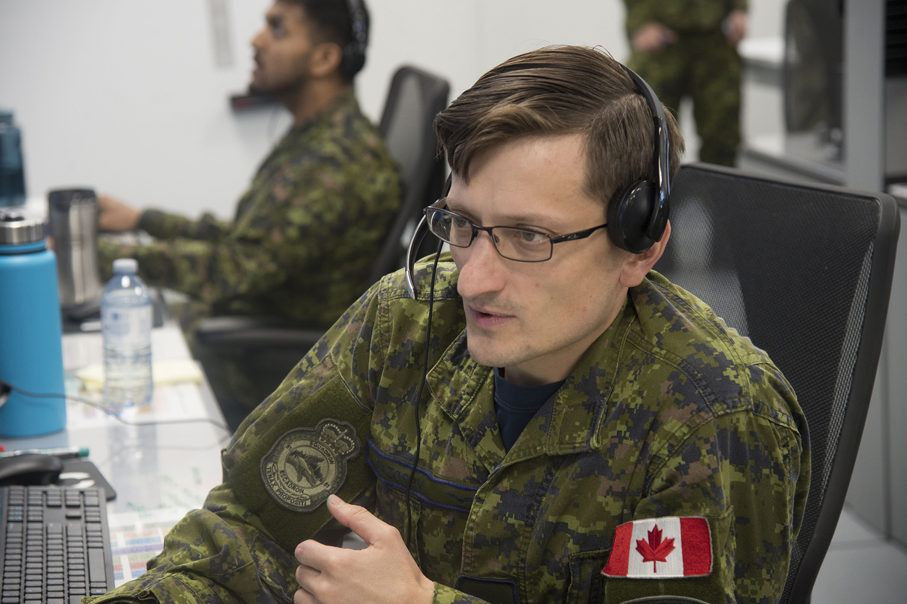 A man wearing a disruptive pattern combat uniform sits at a desk.
