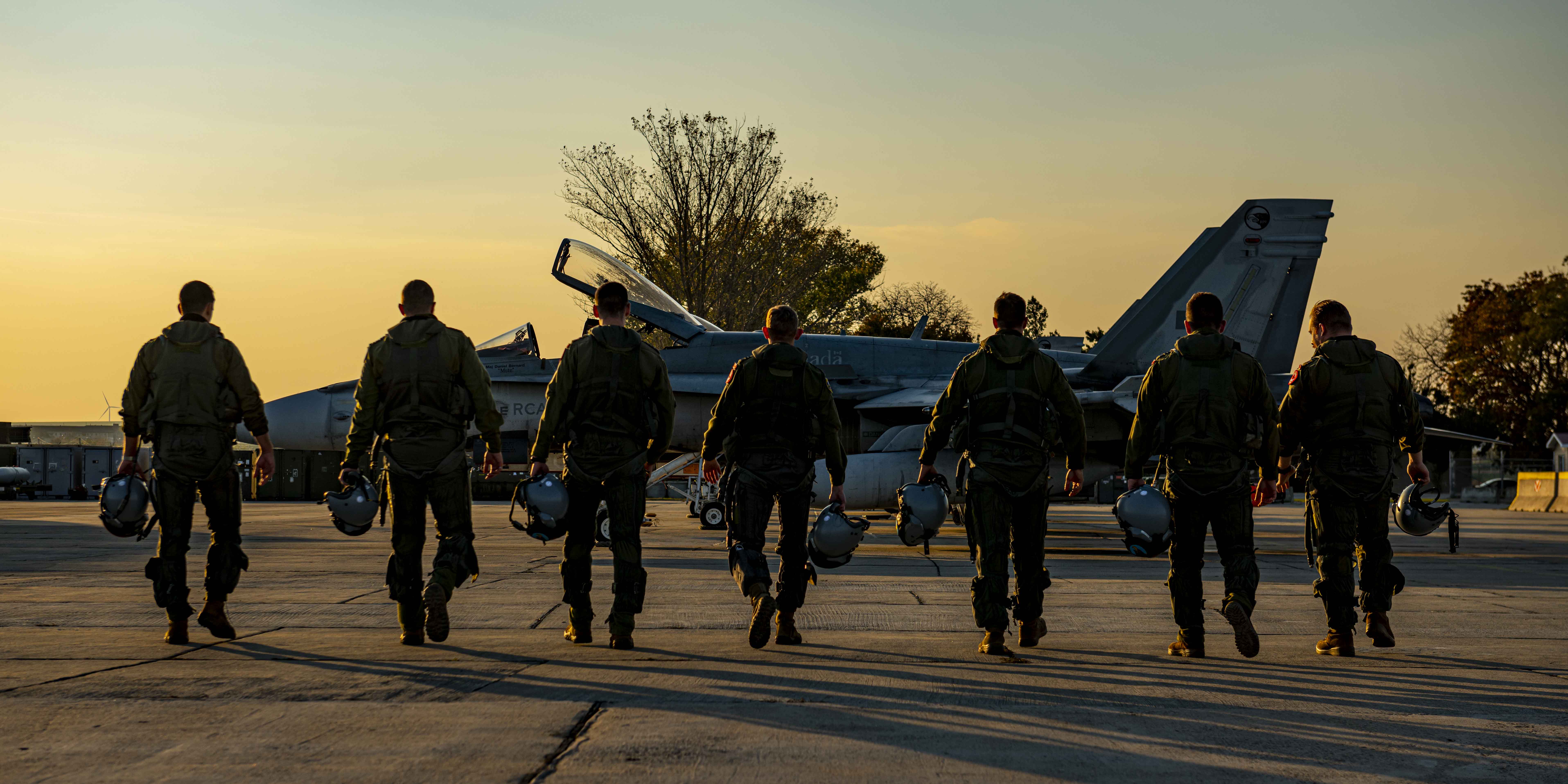 Pilots from 409 Tactical Figher Squadron walk towards a Royal Canadian Air Force CF-188 Hornet at Mihail Kogalniceanu Air Base during Operation REASSURANCE Air Task Force - Romania on October 28, 2021. PHOTO: Aviator Avery Philpott, 4 Wing Imaging